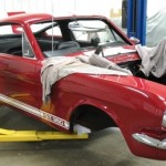 A red mustang sitting on a lift in a garage.