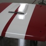 A red and white car with a white stripe on the hood.