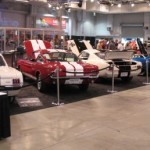 A group of people standing in front of a display of classic cars.