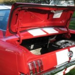 A red and white mustang with its trunk open.