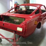 A red mustang is being worked on in a garage.