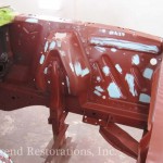 A red car is being painted in a garage.