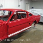 A red mustang is being worked on in a garage.