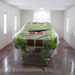 A car is being painted in a garage.