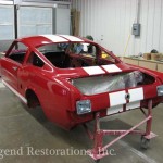 A red and white car is being worked on in a garage.