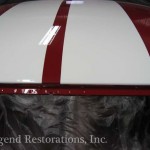 The hood of a red and white car is being painted.