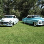 Two classic cars parked on a grassy field.