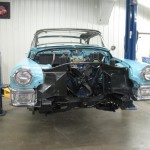 A blue car is being worked on in a garage.