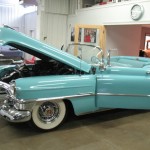 A blue cadillac convertible is parked in a garage.