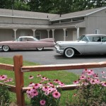 Two classic cars parked in front of a house.