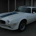 A white pontiac firebird parked in front of a building.