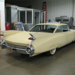 A yellow classic car is parked in a garage.