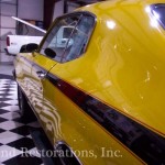 A yellow muscle car is parked in a garage.