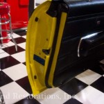 The door of a yellow car with a checkered floor.