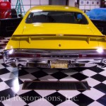 A yellow muscle car in a garage with a checkered floor.