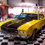 A yellow and black muscle car is parked in a garage.