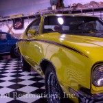 A yellow chevrolet and a black and white checkered floor in a garage.