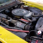 An old yellow car with a hood open.