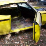 An old yellow muscle car with the door open.