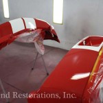 A red and white car being painted in a garage.