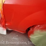 A red car being painted with red paint.