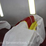 A red and yellow chair is being painted in a room.