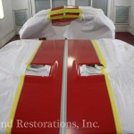 A red and yellow car being painted in a garage.