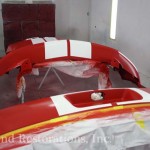 A red and white car being painted in a garage.