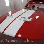 A red and white car being painted in a garage.