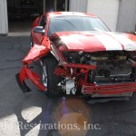 A red car with its hood open is parked in a garage.