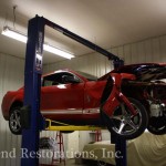 A red mustang sitting on a lift in a garage.