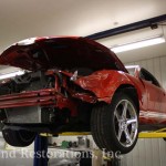 A red ford mustang sitting on a lift in a garage.