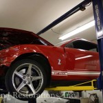 A red mustang is being lifted into a garage.