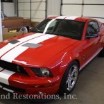 A red and white mustang is parked in a garage.