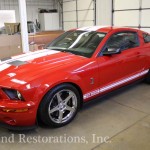 A red and white mustang is parked in a garage.