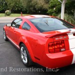 A red and white mustang parked in front of a house.