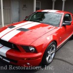 A red and white ford mustang parked in front of a building.